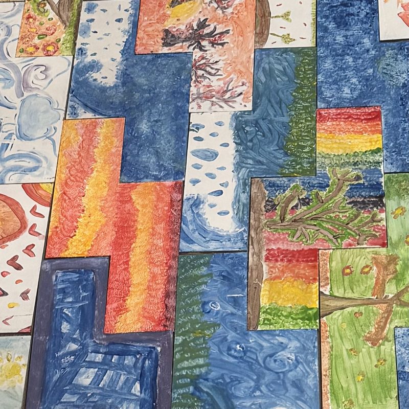 Mural colectivo de estudiantes de primaria: piezas pintadas en azules, naranjas y verdes encastradas como un rompecabezas